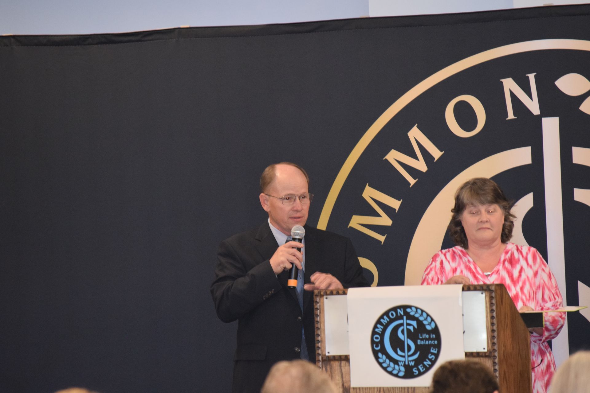 A man and woman are standing at a podium in front of a sign that says commons
