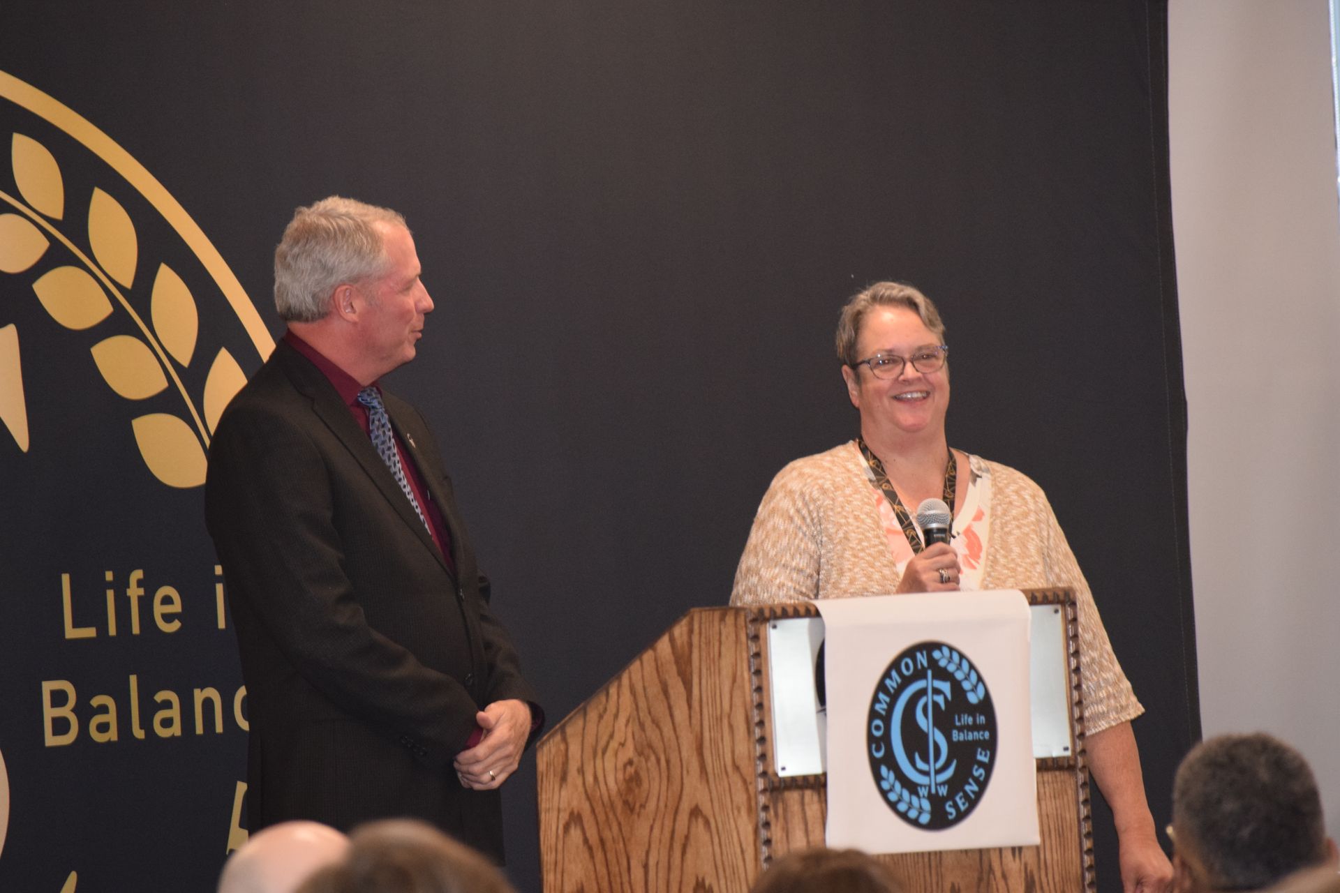 A man and a woman are standing at a podium with a sign that says life i balance
