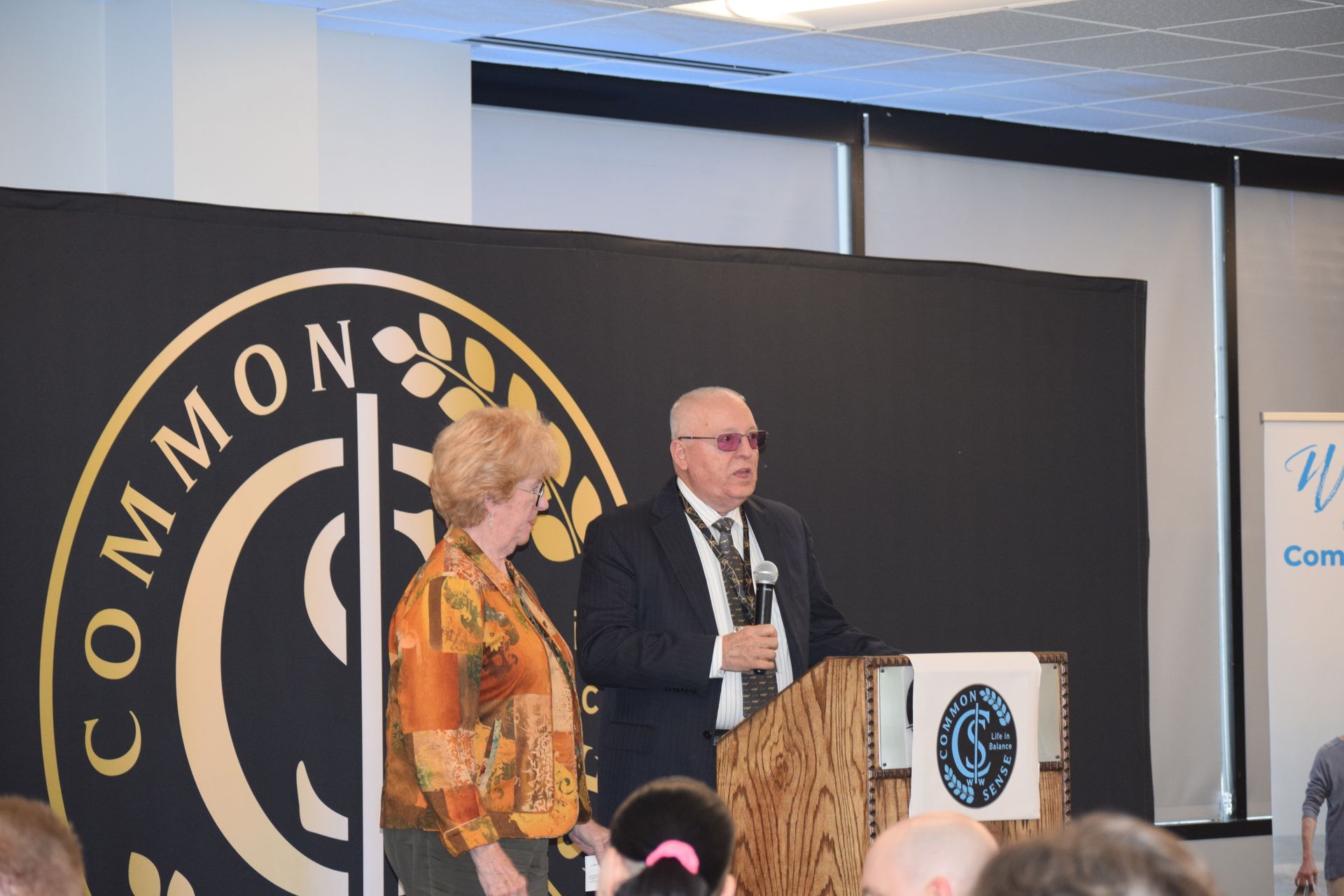 A man and woman are standing at a podium in front of a sign that says common