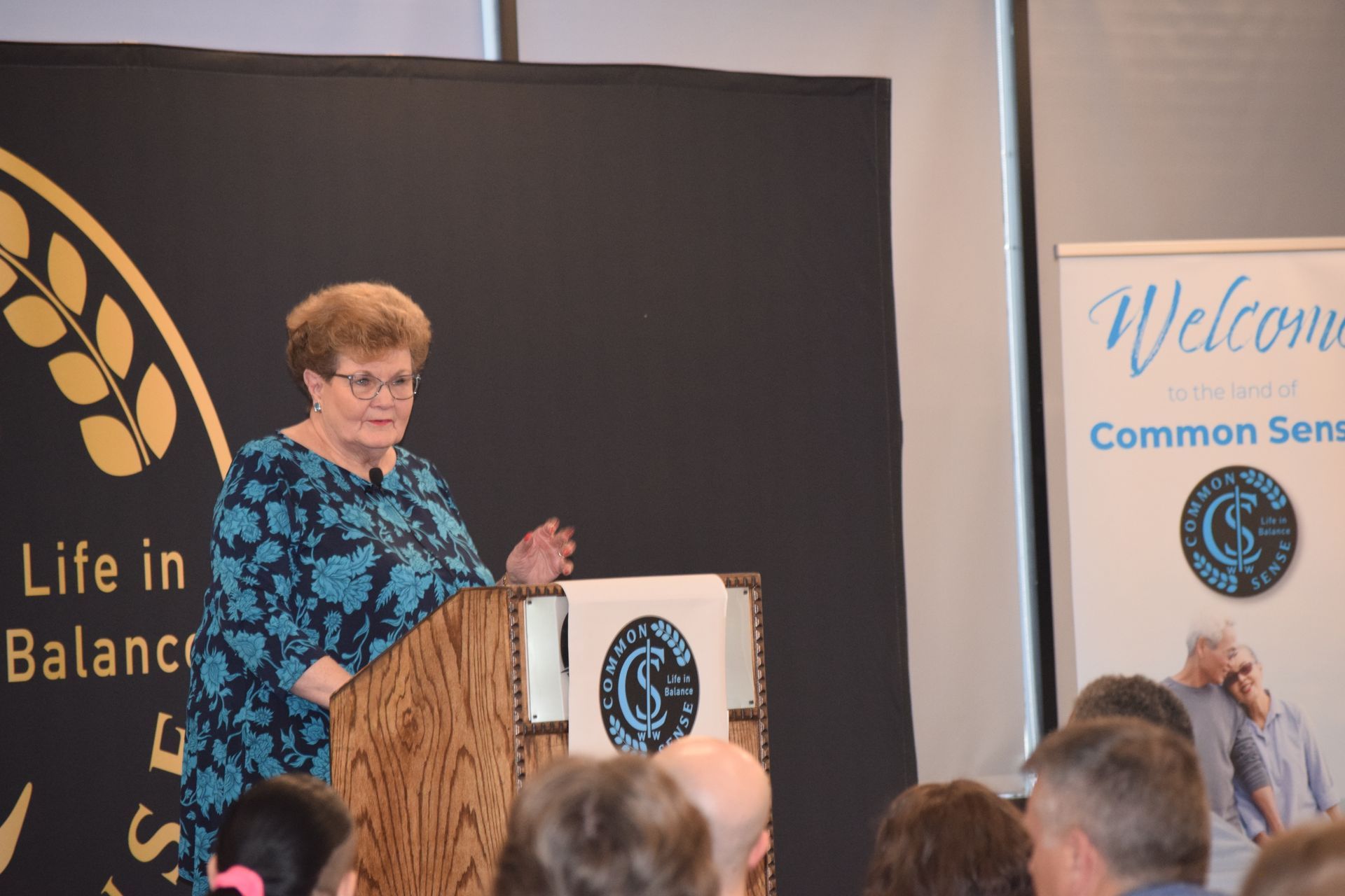 A woman is standing at a podium talking to a group of people.
