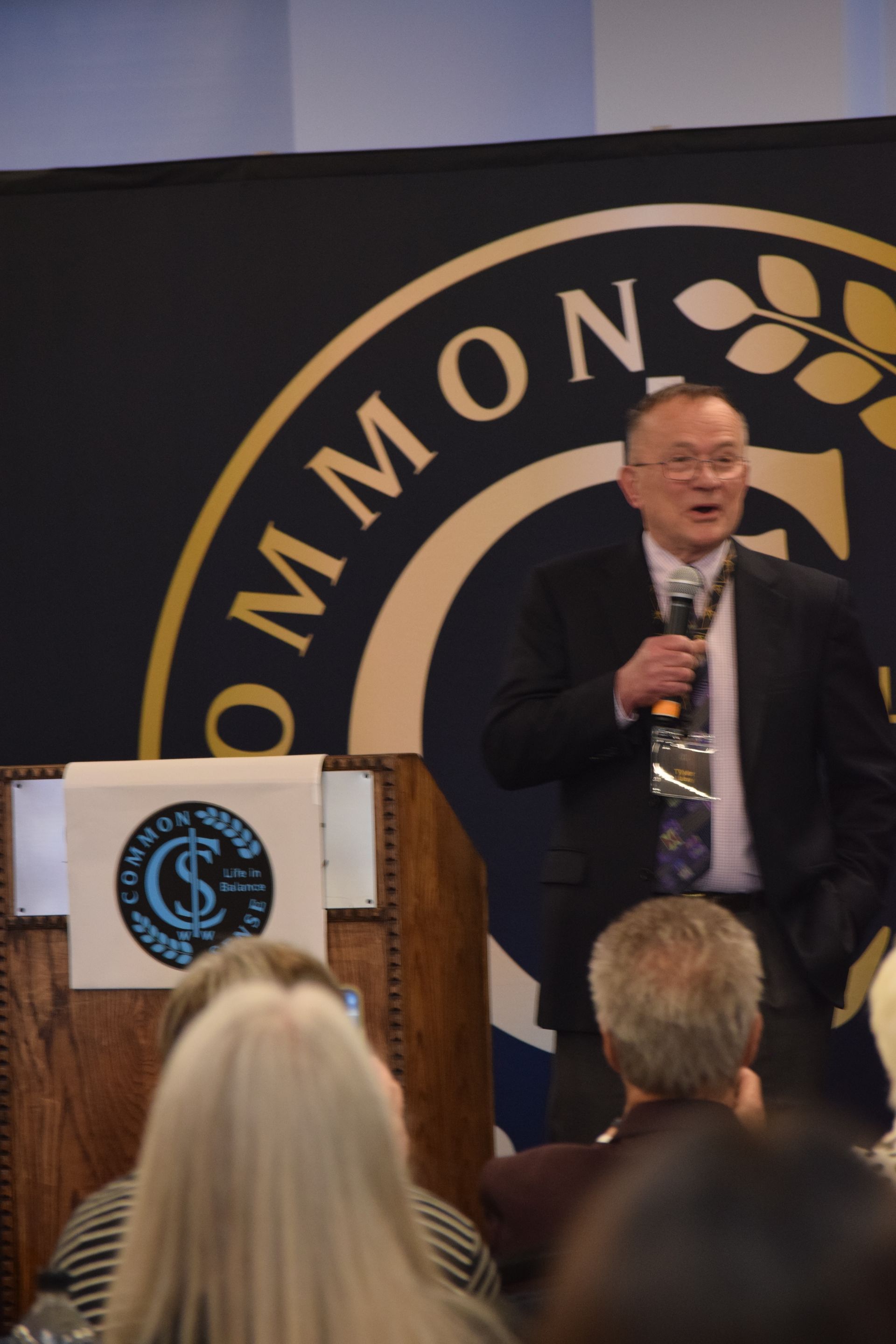 A man stands at a podium in front of a sign that says common