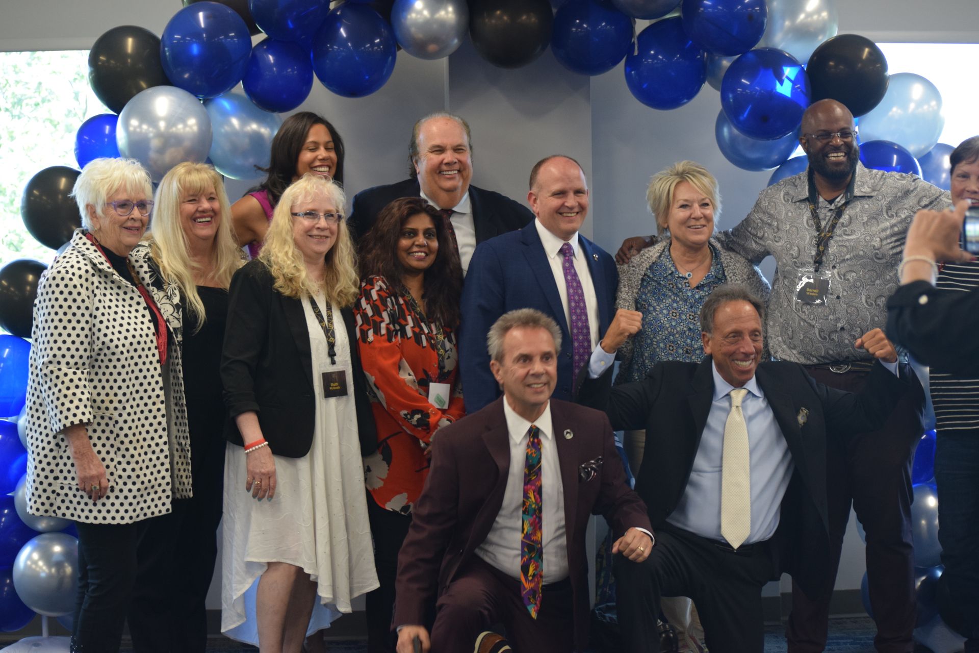 A group of people are posing for a picture in front of balloons.