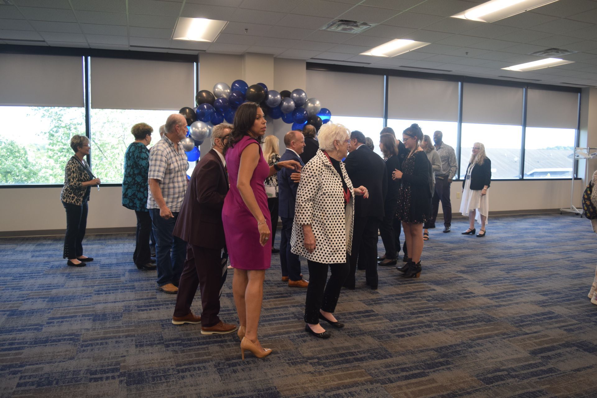 A group of people are standing in a room with balloons in the background.