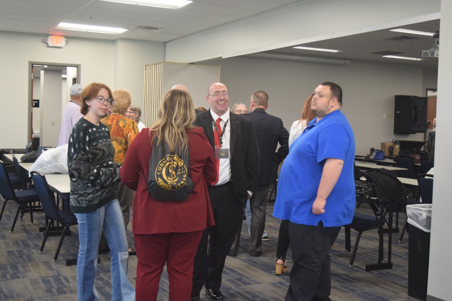 A group of people are standing in a room talking to each other.