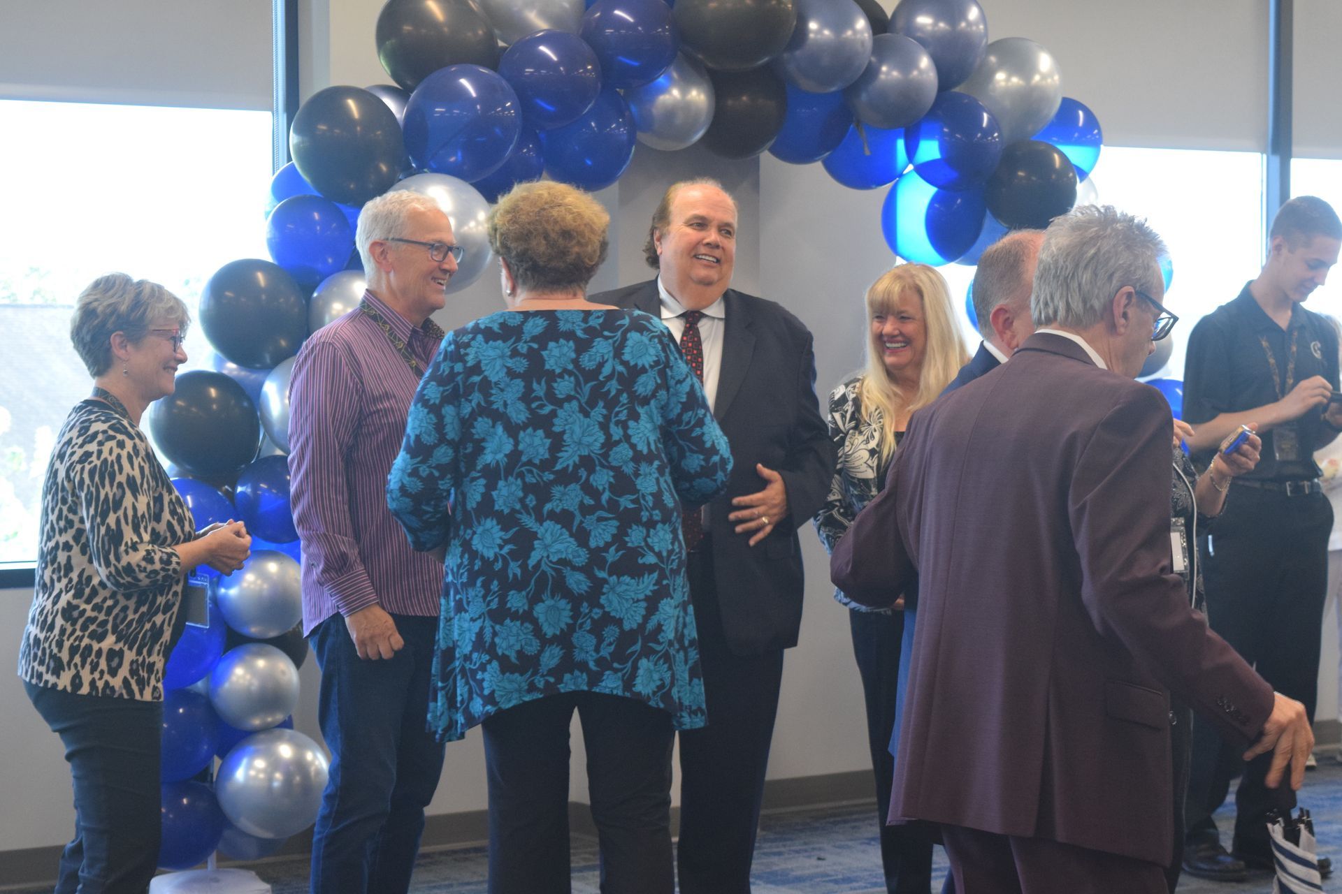 A group of people are standing in a room with balloons.