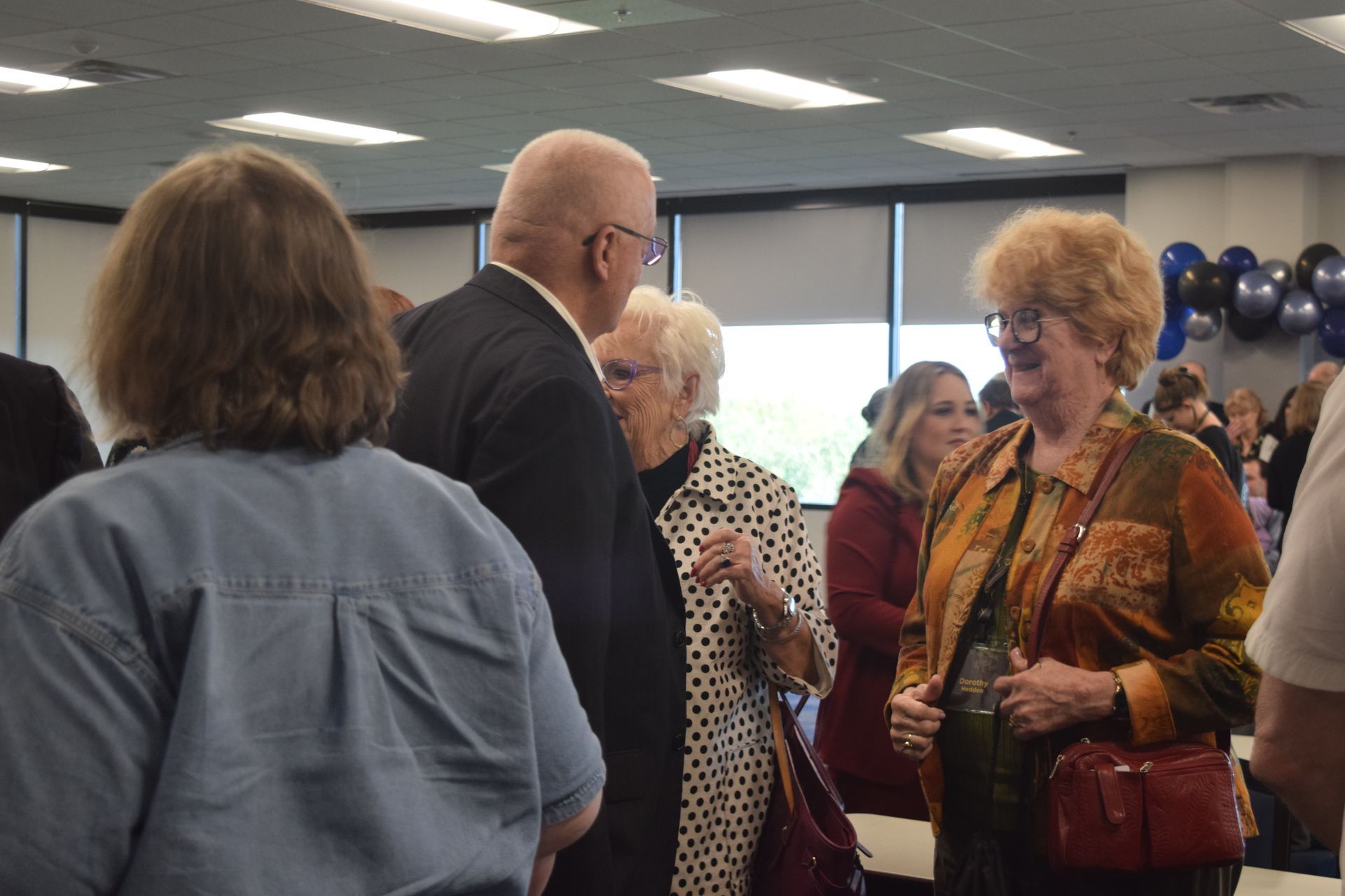 A group of people are standing in a room talking to each other.