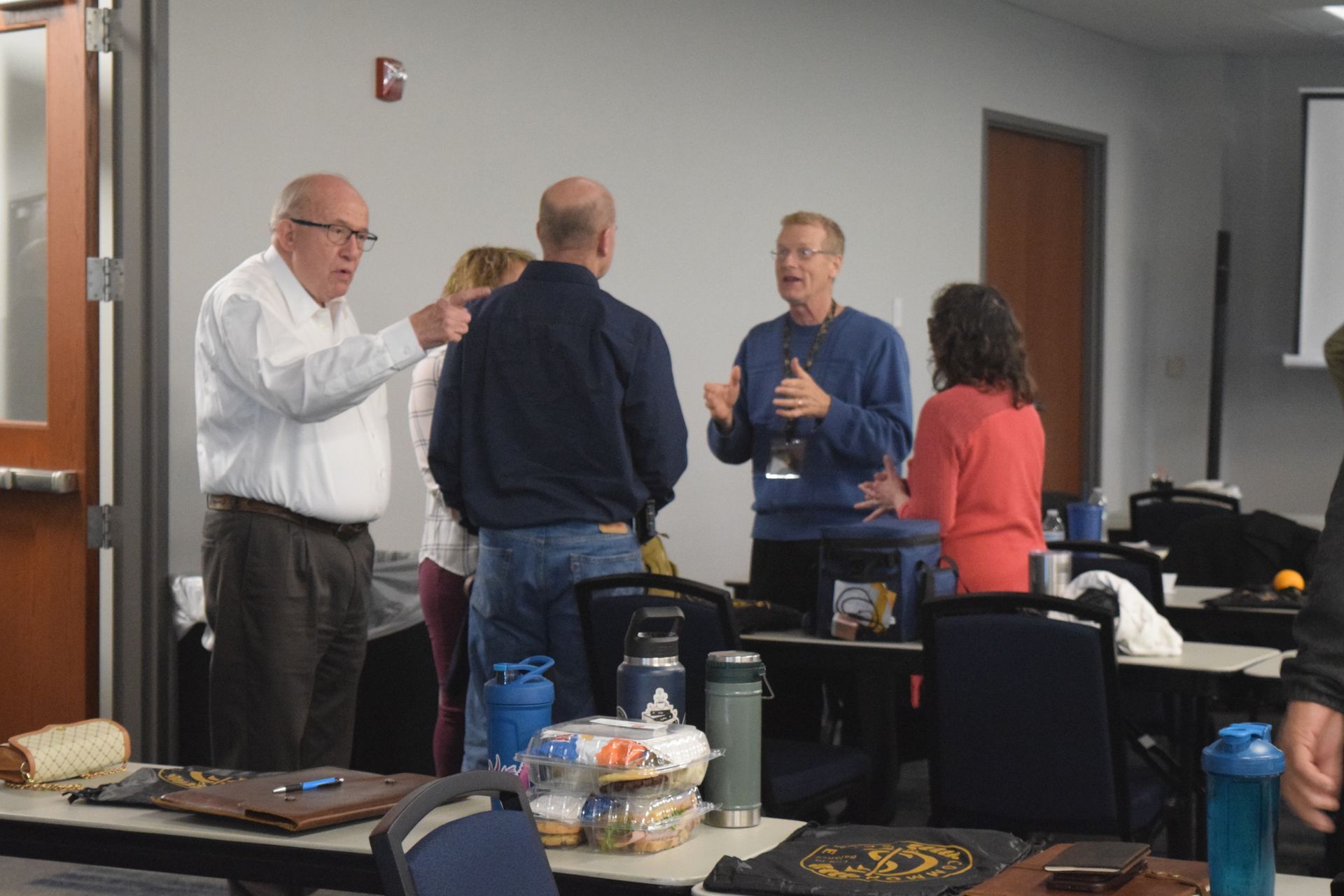 A group of people are standing in a room talking to each other.