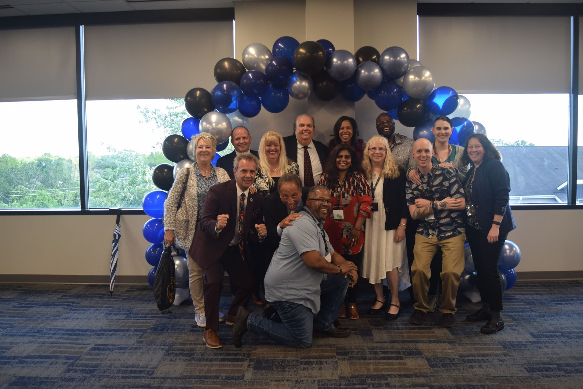 A group of people are posing for a picture in front of a balloon arch.
