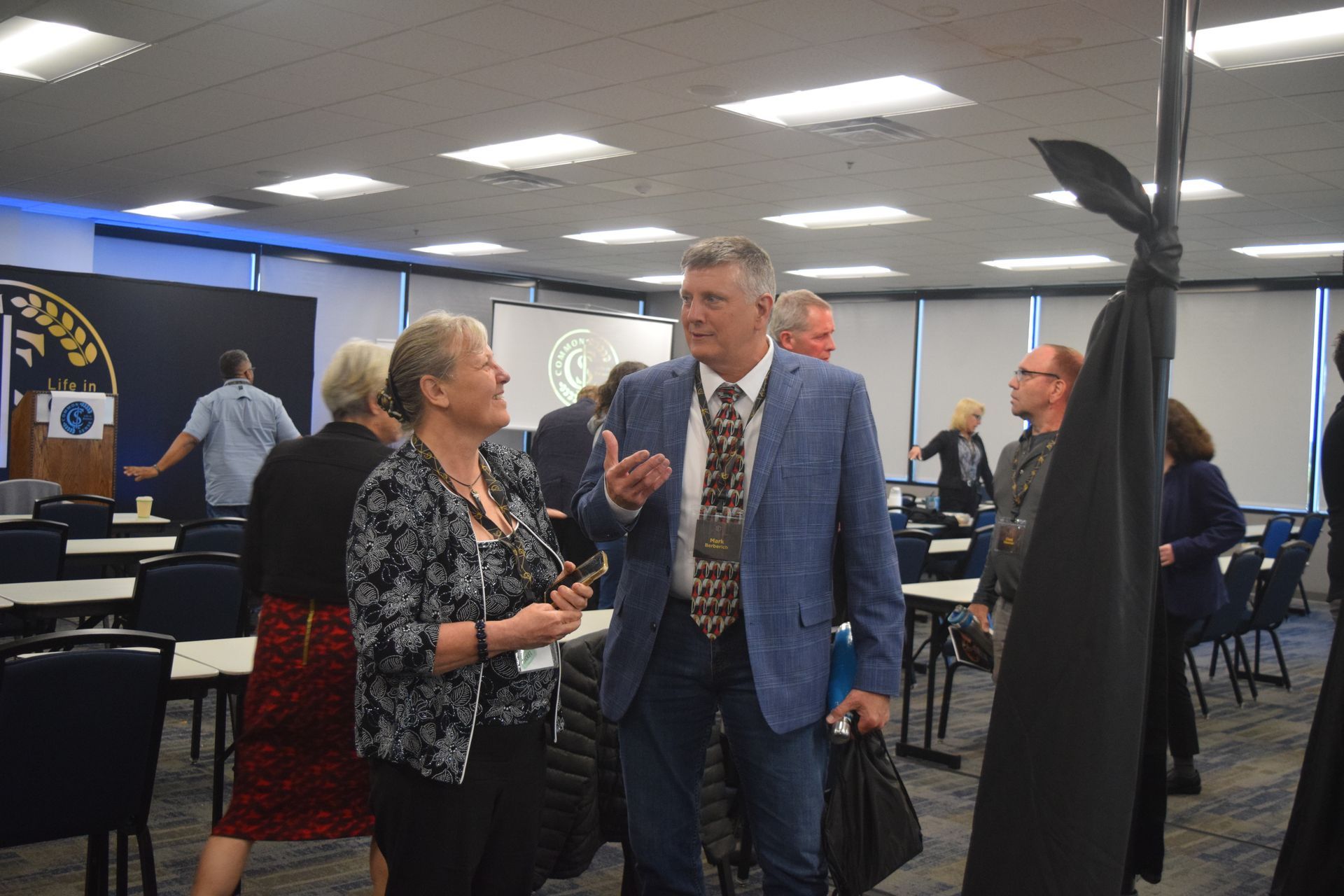 A group of people are standing in a room talking to each other.