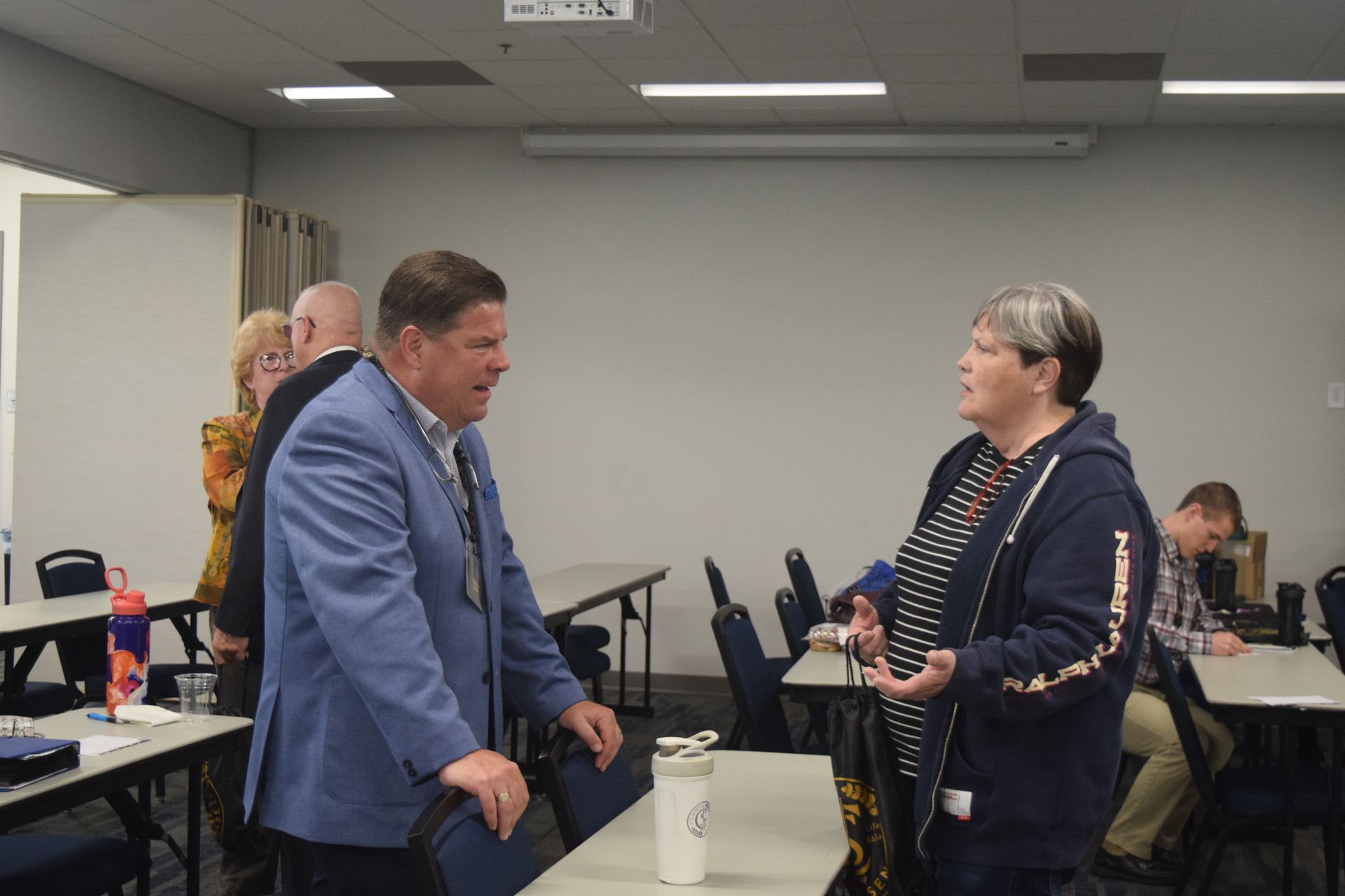 A man and a woman are standing in a room talking to each other.