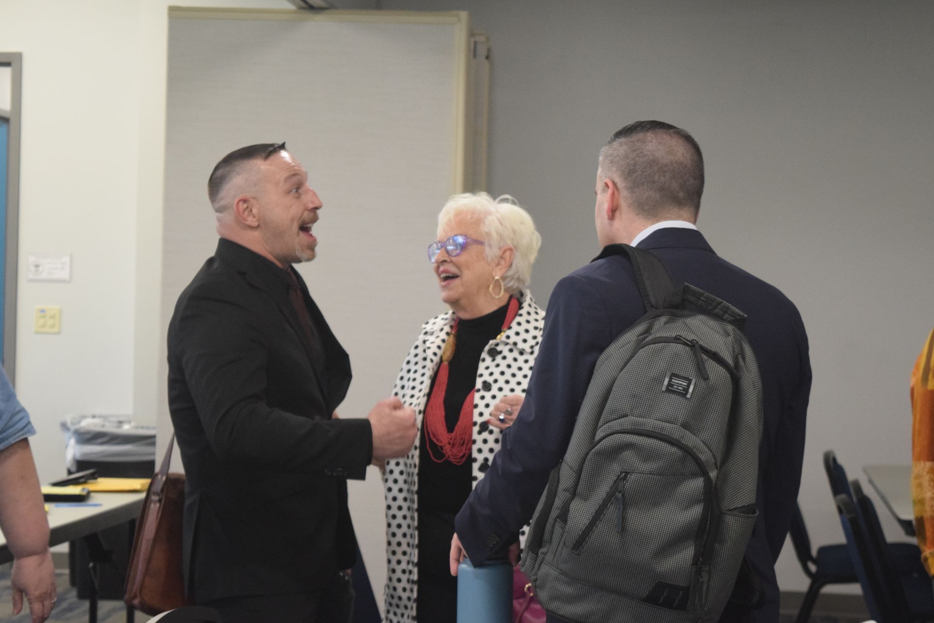 A group of people are standing in a room talking to each other.