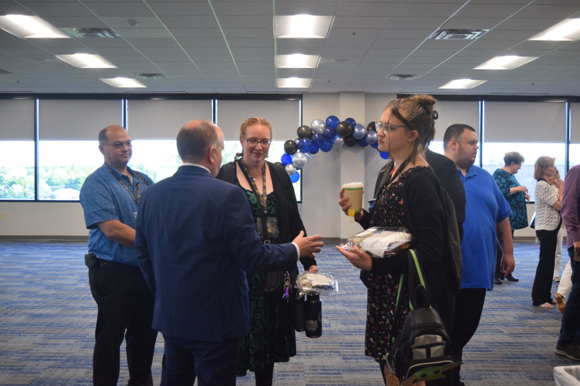 A group of people are standing in a room talking to each other.