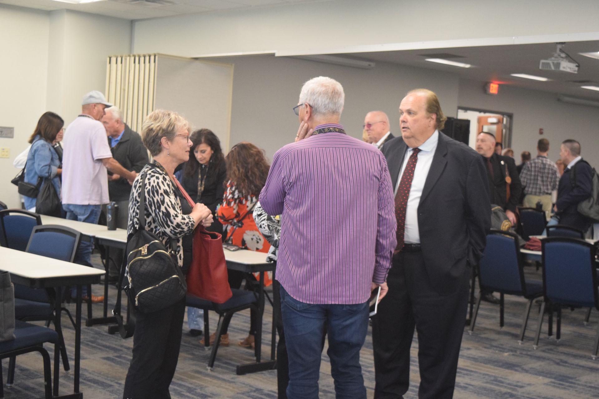 A group of people are standing in a room talking to each other.