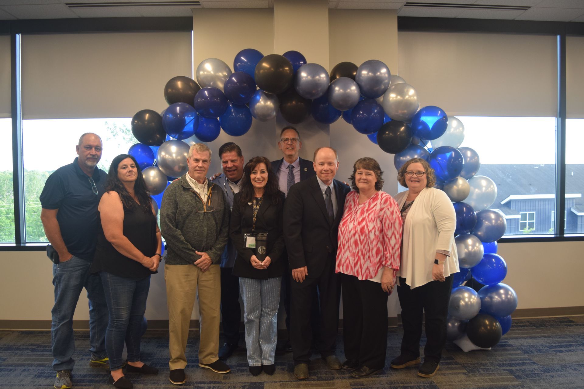 A group of people are posing for a picture in front of a balloon arch.