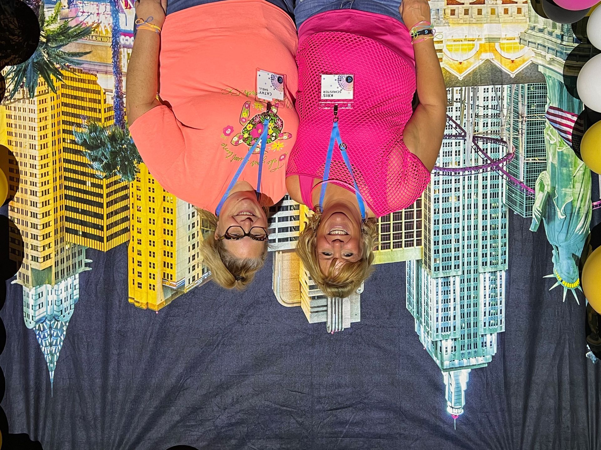 Two women are posing for a picture in front of a city skyline.