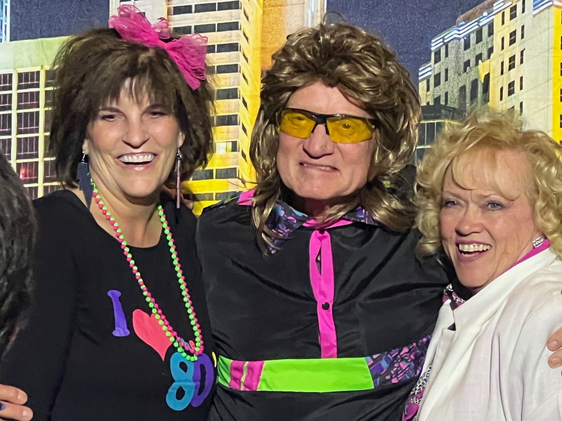 A group of people are posing for a picture and one of them is wearing an 80 's costume.