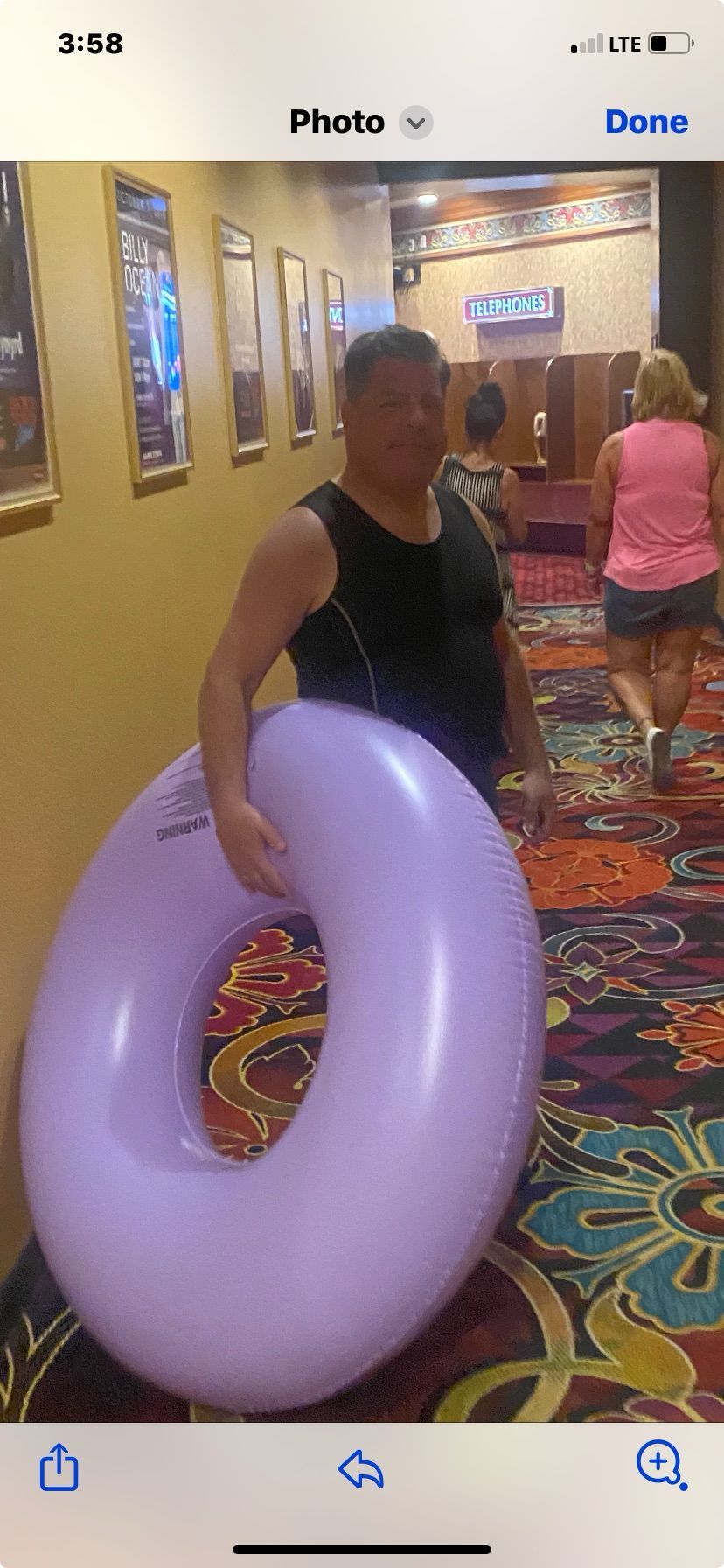 A man is holding a purple inflatable ring in a hallway.