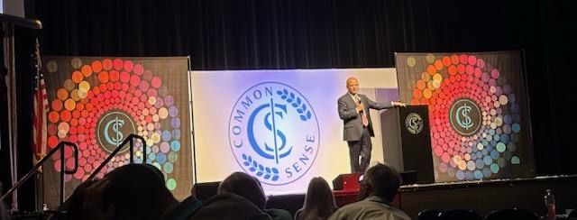A man is giving a speech on a stage in front of a crowd.