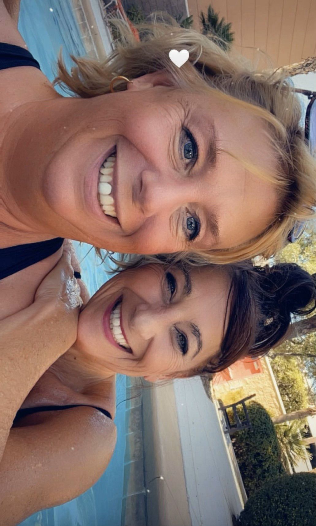 Two women are standing next to each other in a pool and smiling.