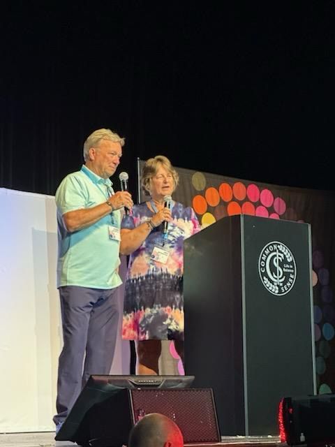 A man and a woman are standing at a podium speaking into microphones