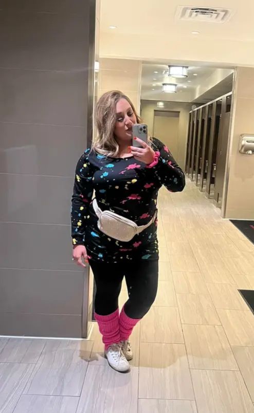 A woman is taking a selfie in a public restroom.