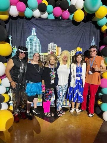 A group of people are posing for a picture in front of balloons.