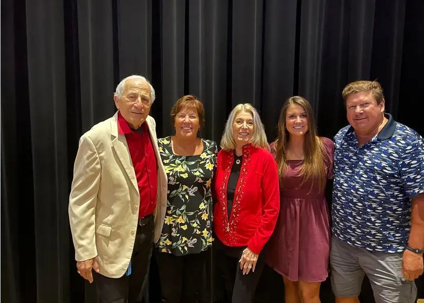 A group of people are posing for a picture in front of a black curtain.
