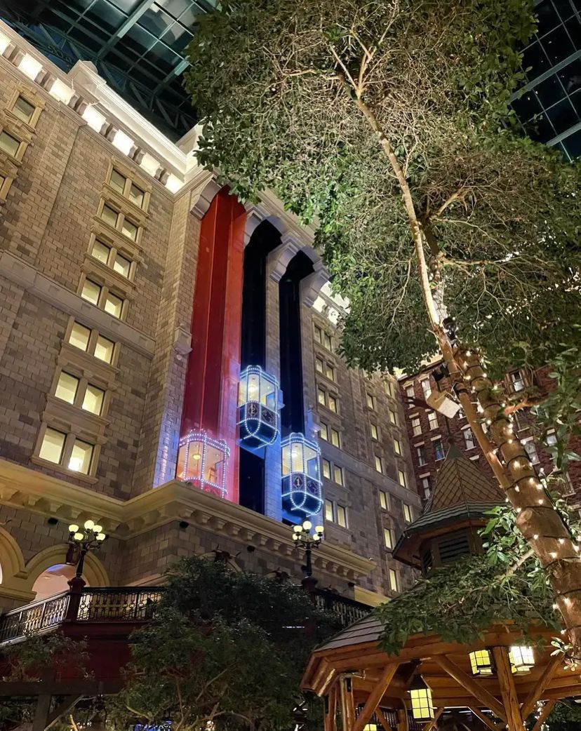 A large building with trees in front of it is lit up at night.