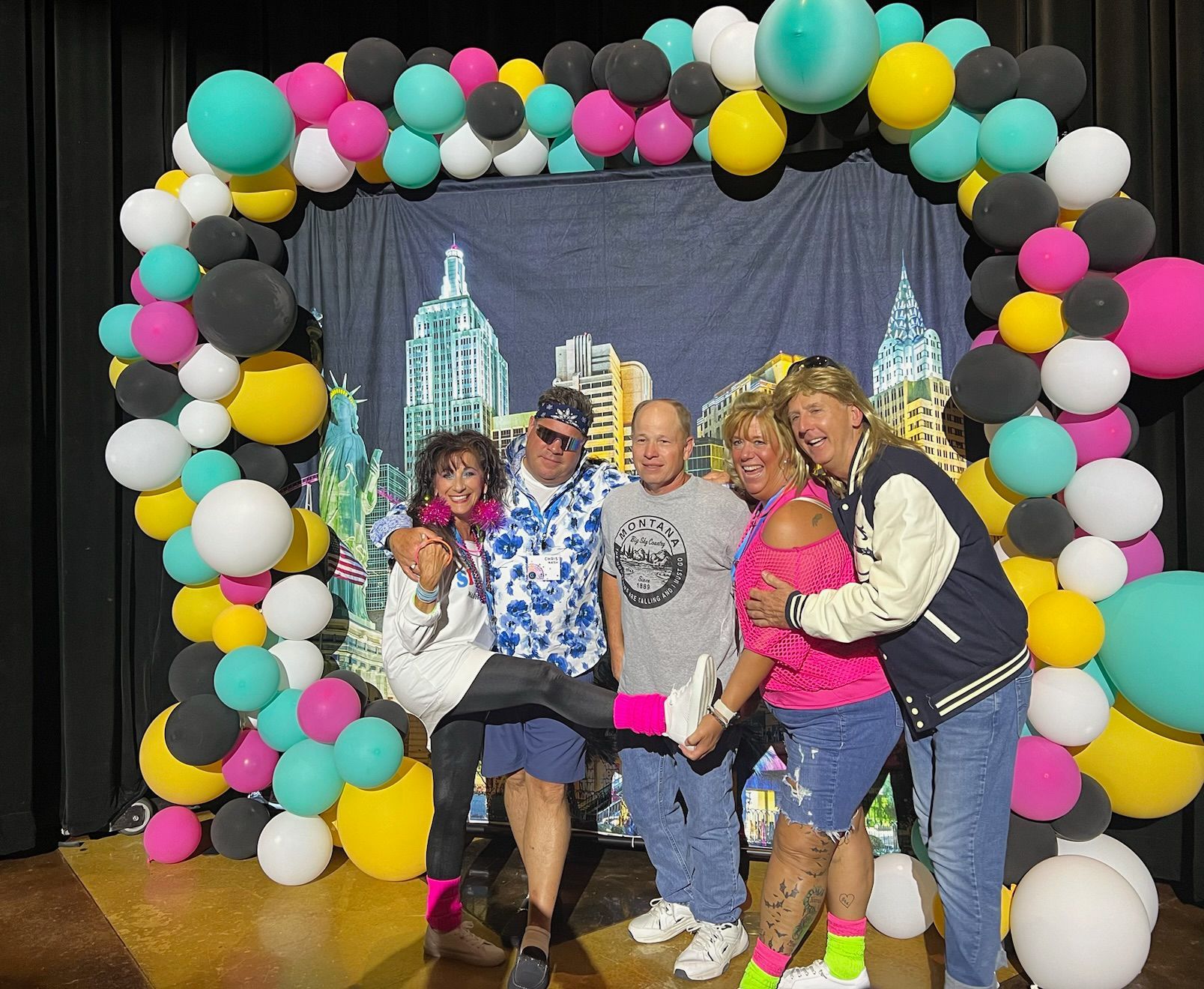 A group of people are posing for a picture in front of a balloon arch.