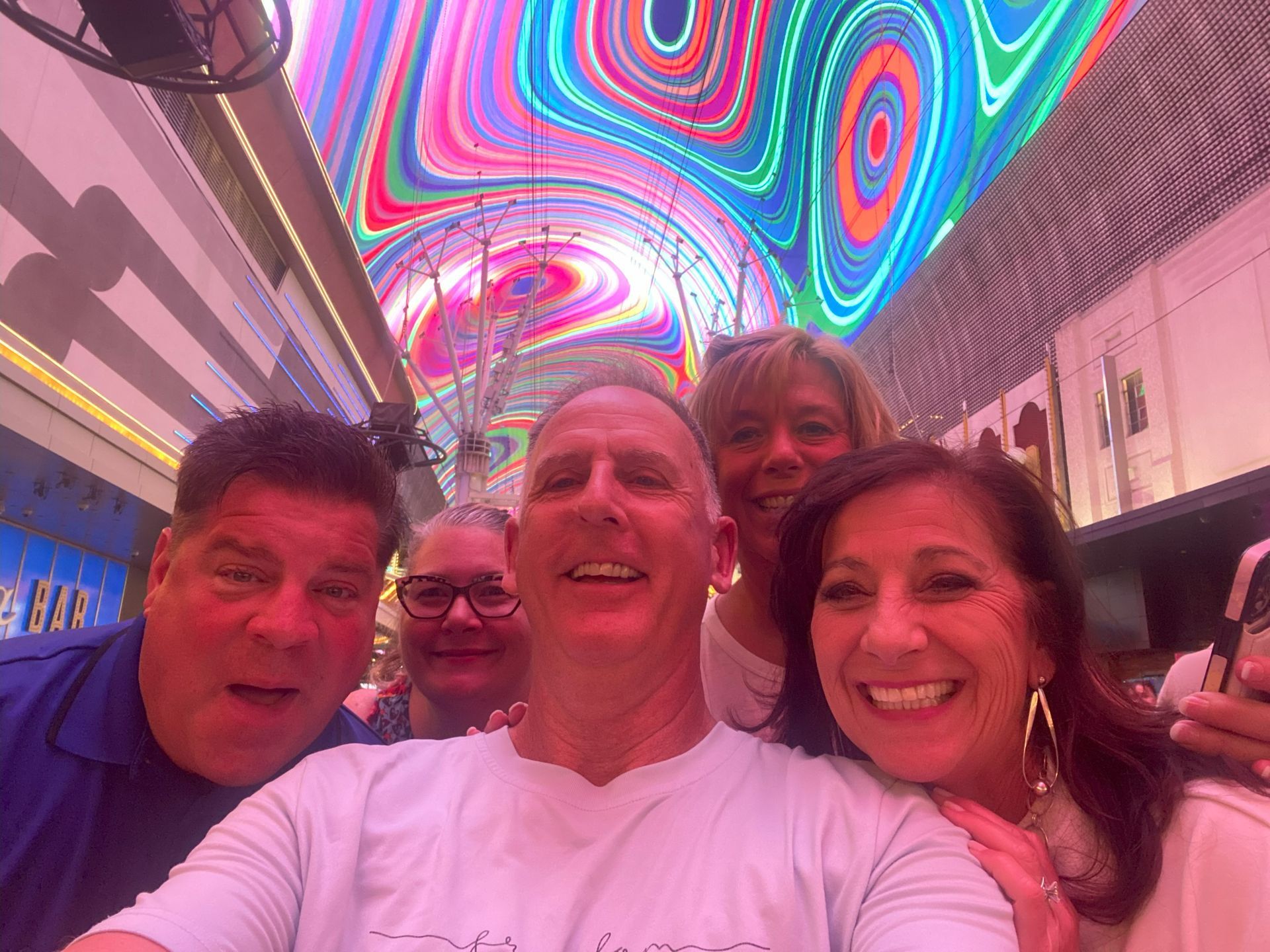 A group of people are posing for a picture in front of a colorful ceiling.