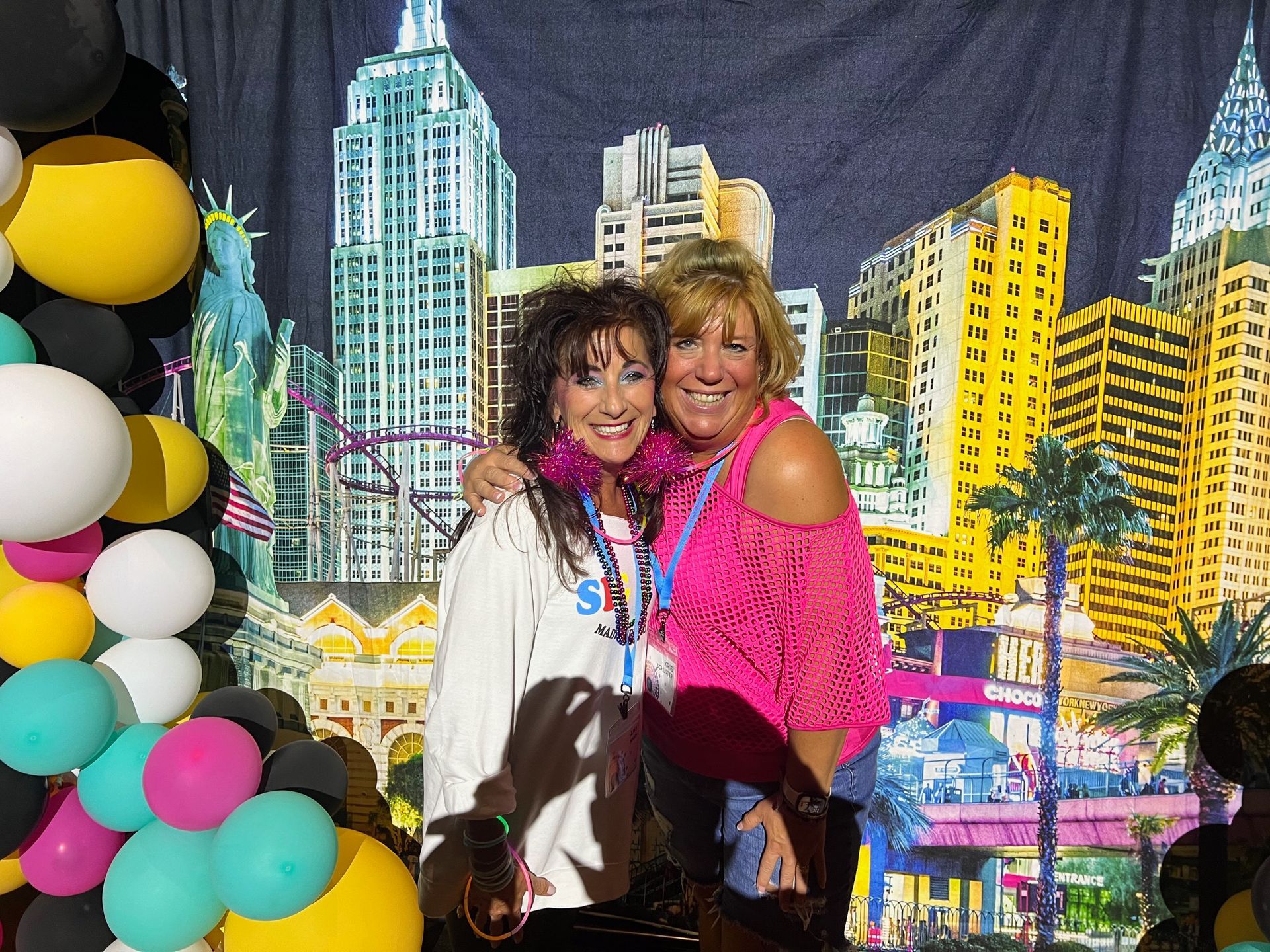 Two women posing for a picture with balloons in the background