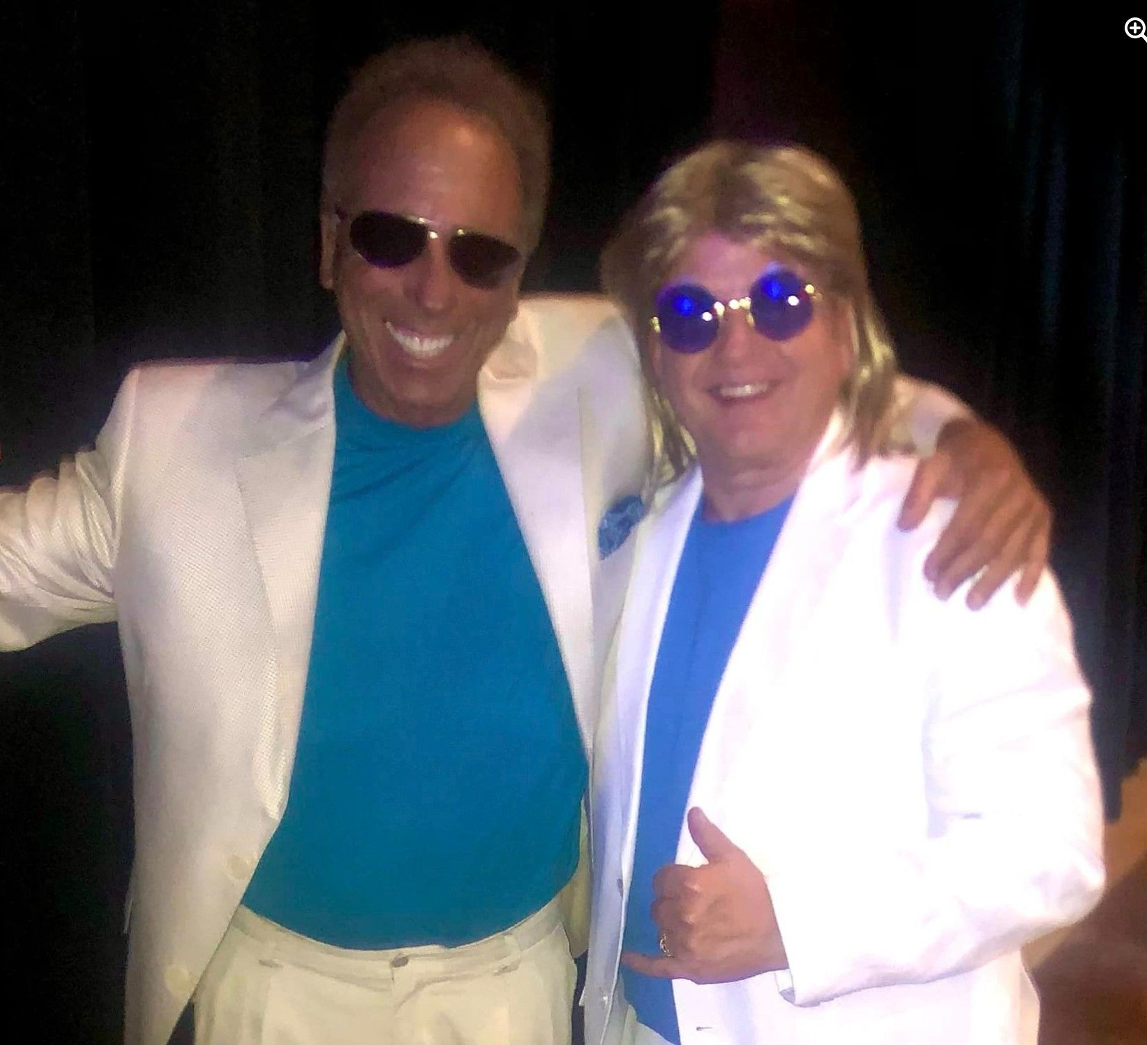 Two men posing for a picture with one wearing sunglasses