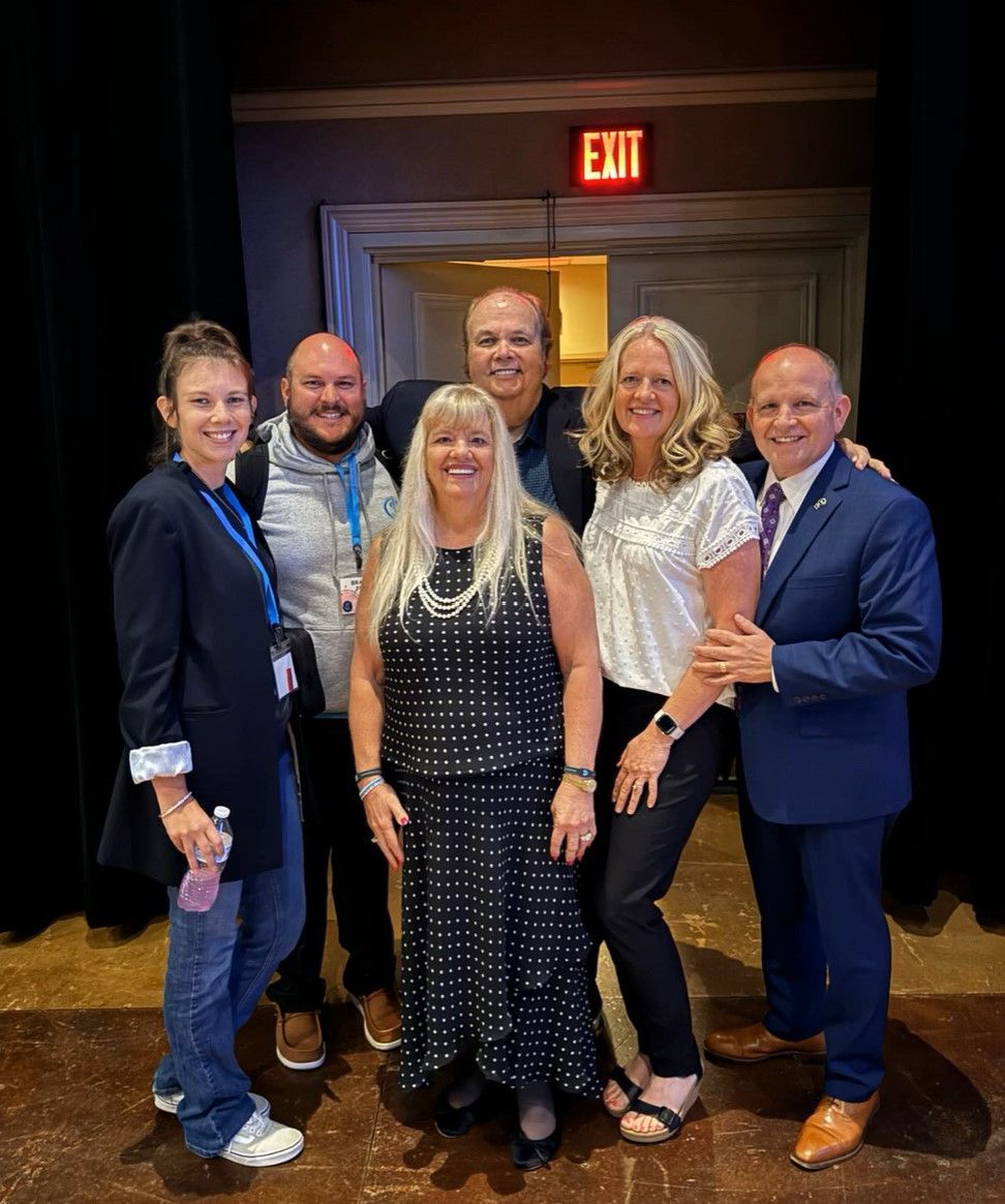 A group of people are posing for a picture in front of an exit sign.