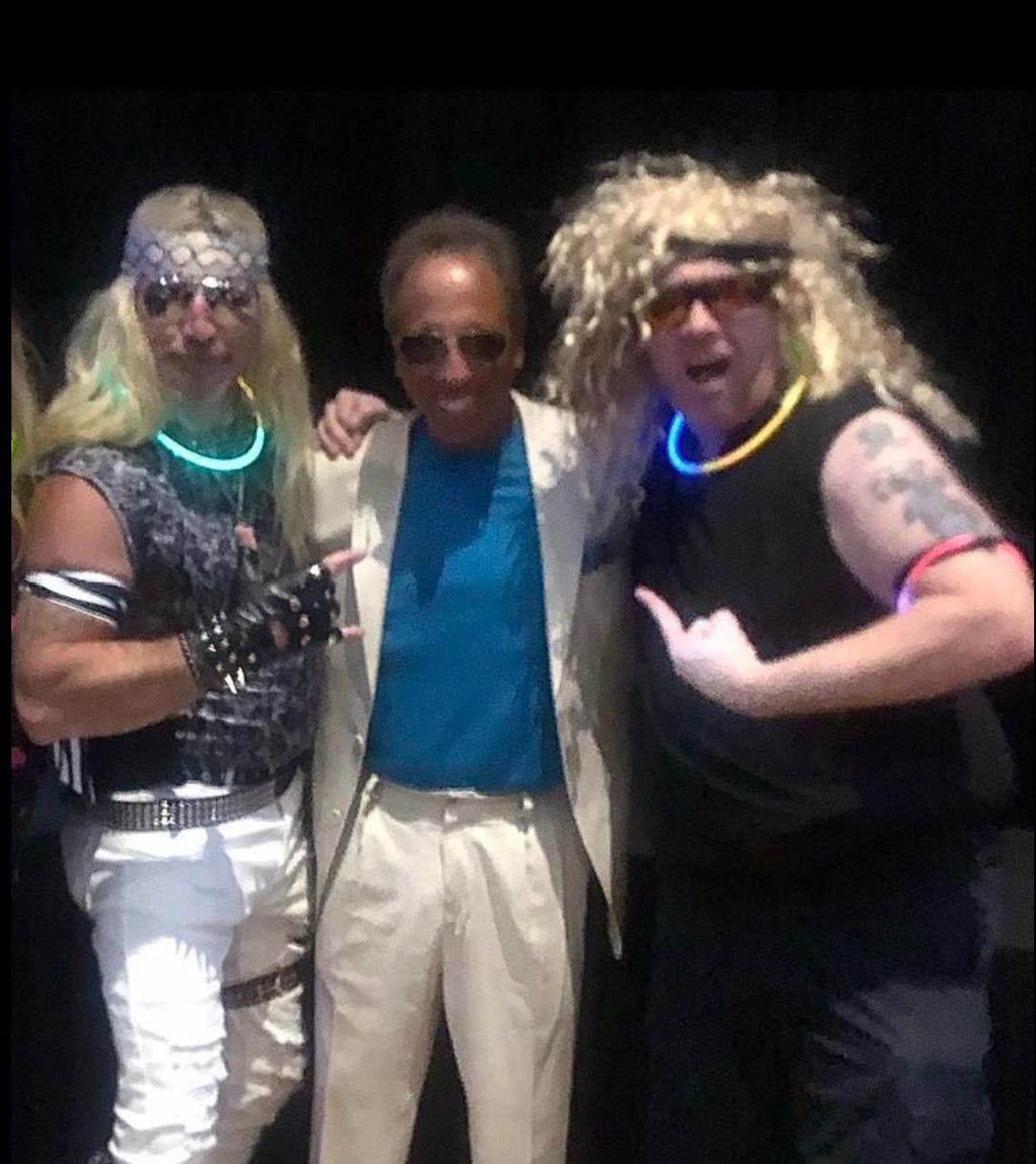 Three men posing for a picture with one wearing a wig