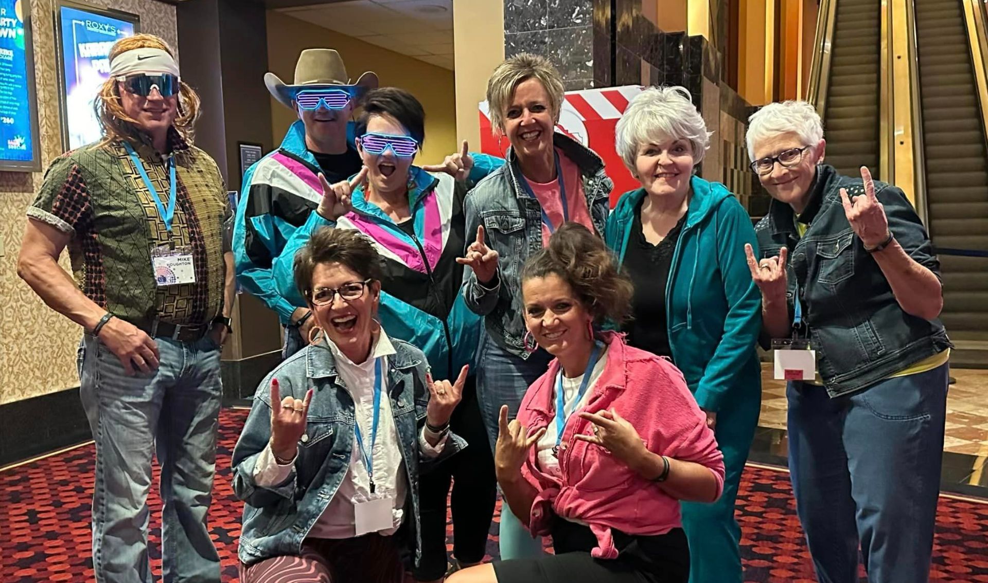 A group of people dressed in 80s costumes are posing for a picture.