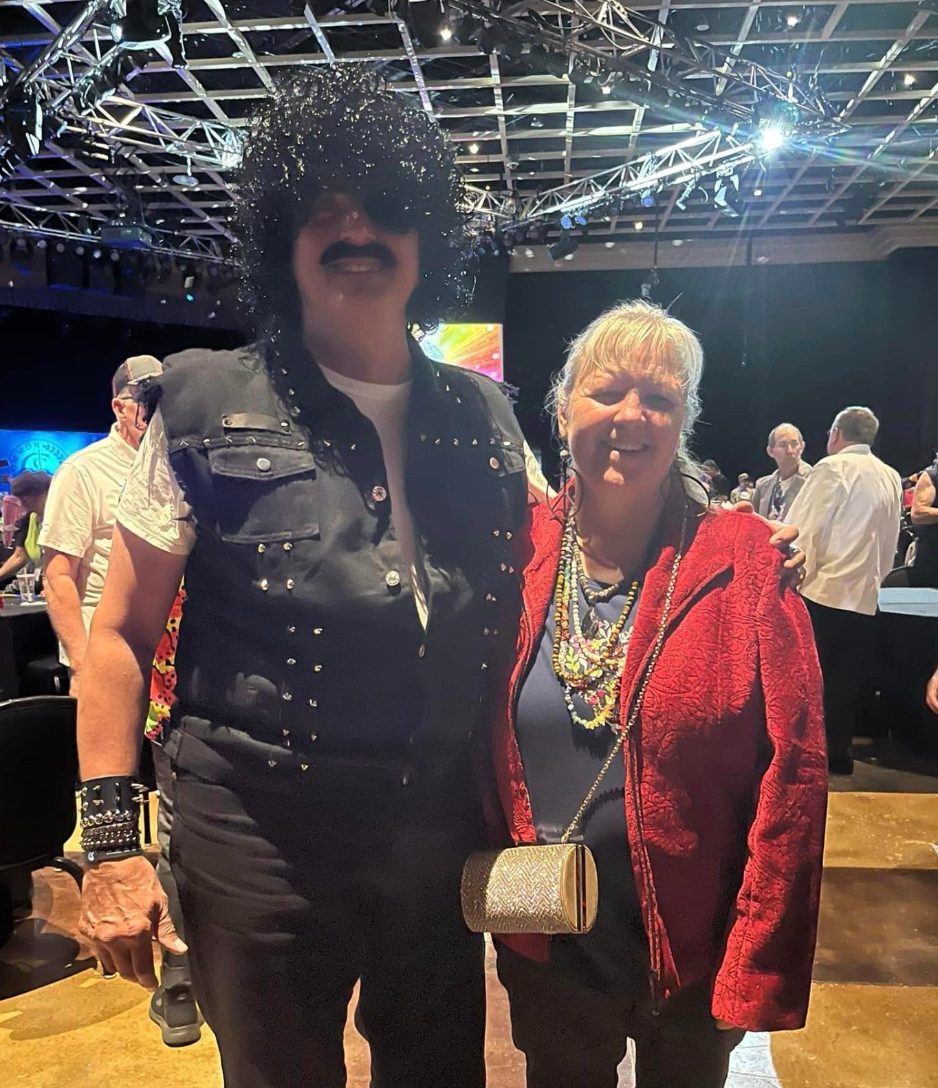 A man in a wig is posing for a picture with a woman in a red jacket
