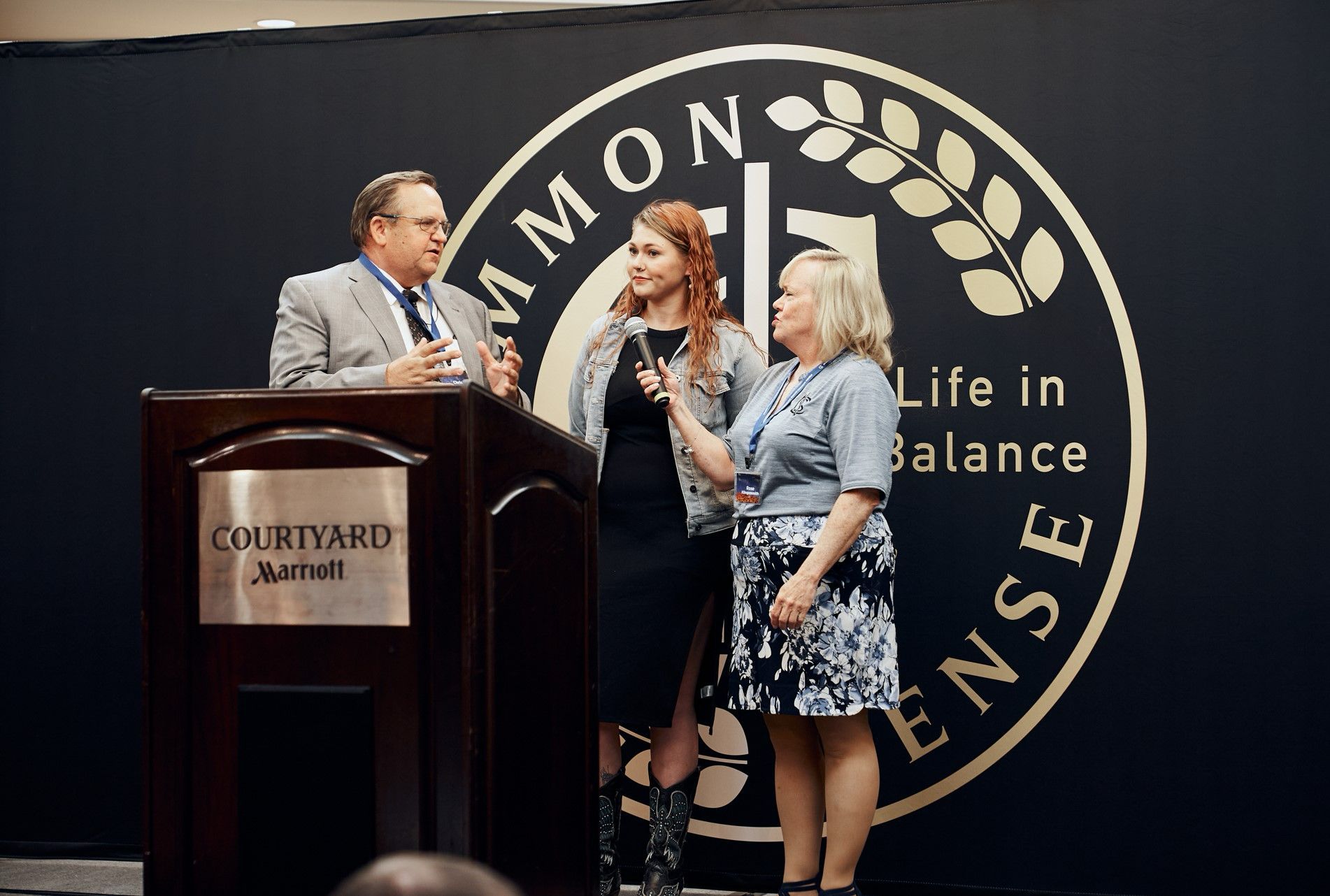 A man and two women are standing at a podium in front of a sign that says life in balance.