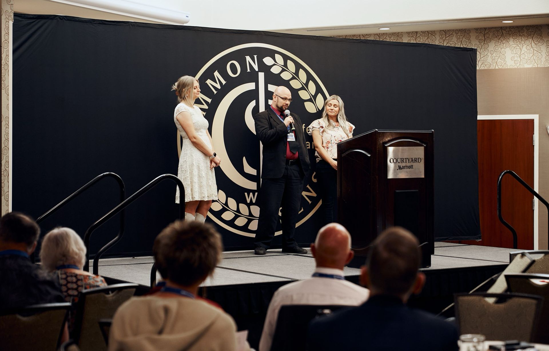 A man is standing on a stage giving a speech to a group of people.