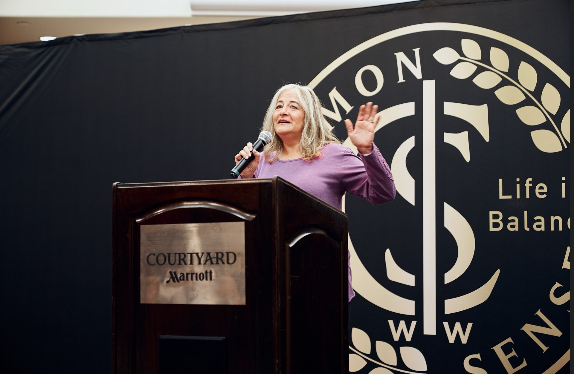 A woman is standing at a podium holding a microphone.