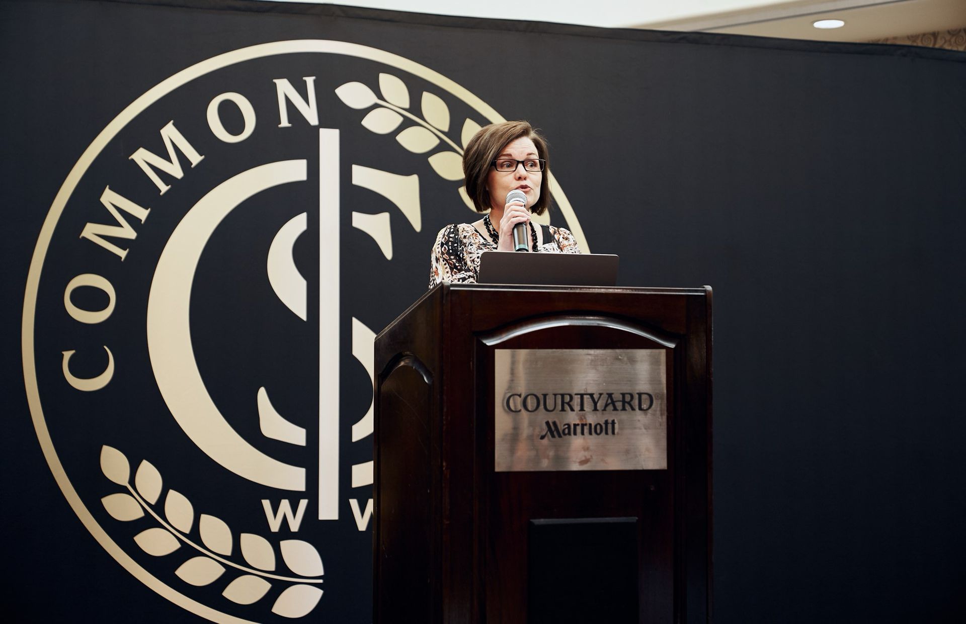 A woman is standing at a podium in front of a sign that says common