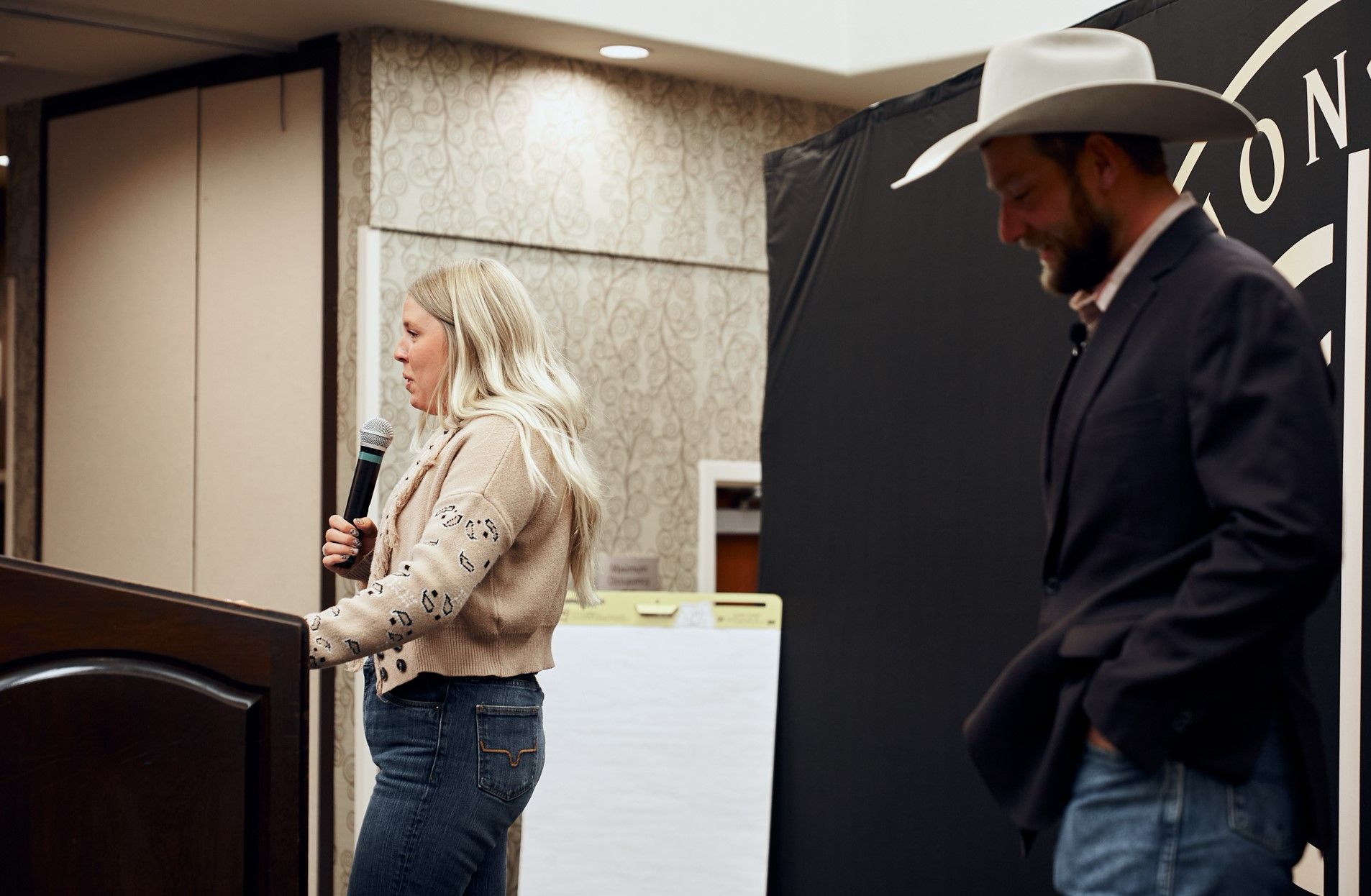 A man and a woman are standing next to each other and the woman is holding a microphone.