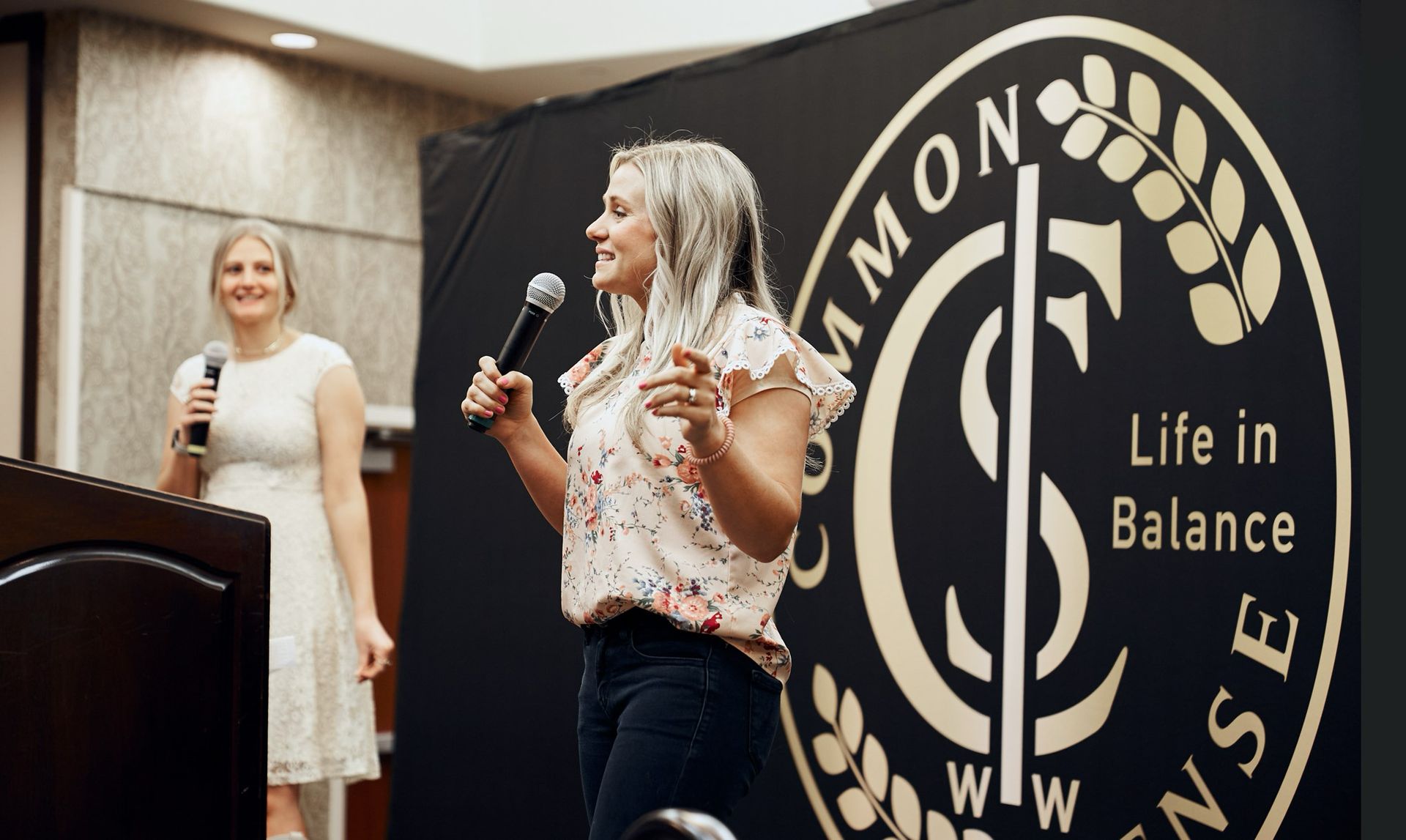 A woman is standing at a podium holding a microphone.