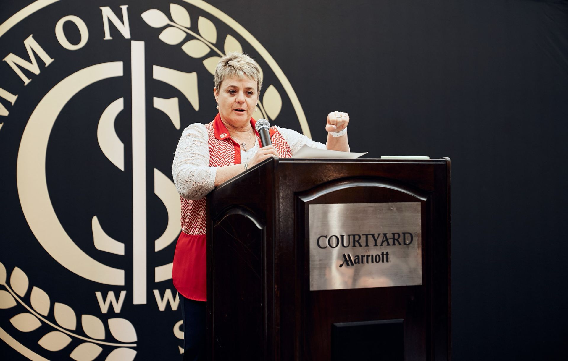 A woman is standing at a podium in front of a courtyard marriott logo.
