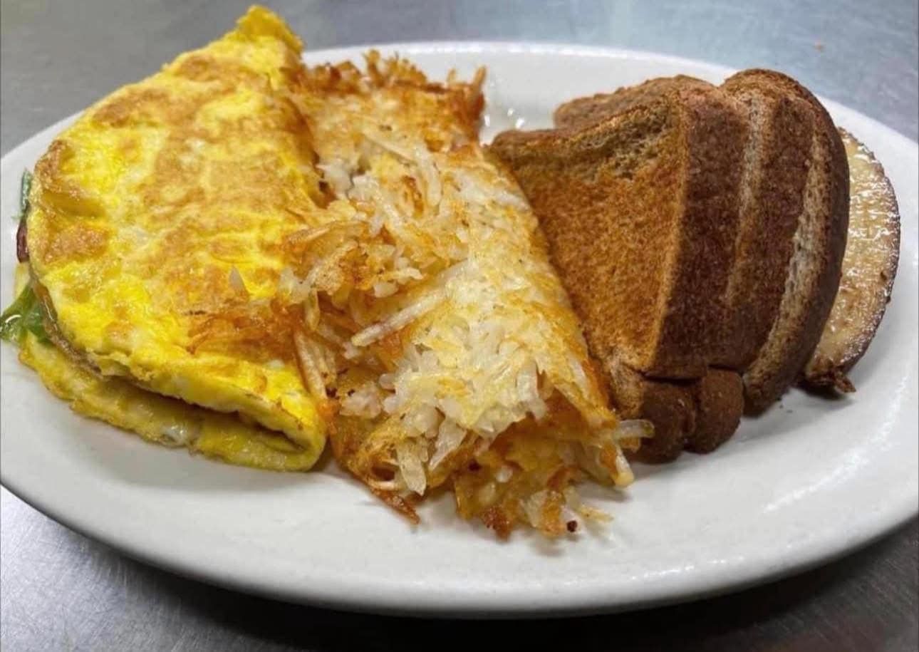 A white plate topped with an omelet , hash browns and toast.