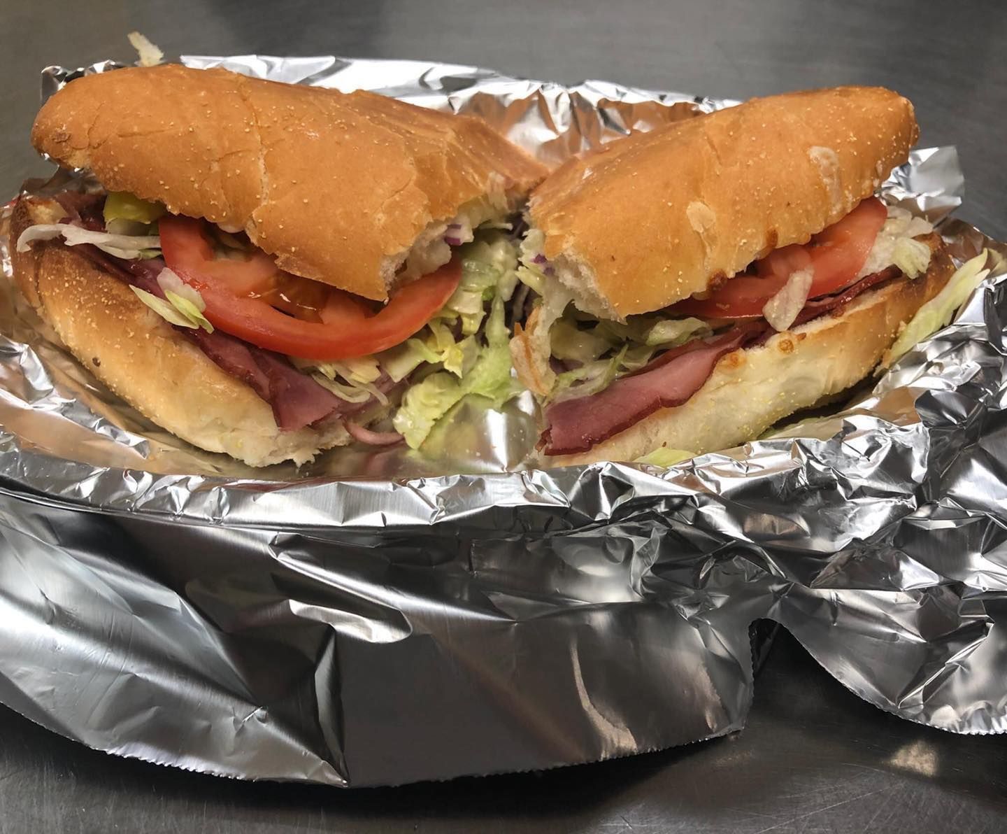 A sub sandwich is wrapped in tin foil on a table.