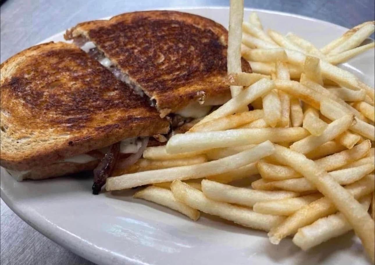 A grilled cheese sandwich and french fries on a white plate.