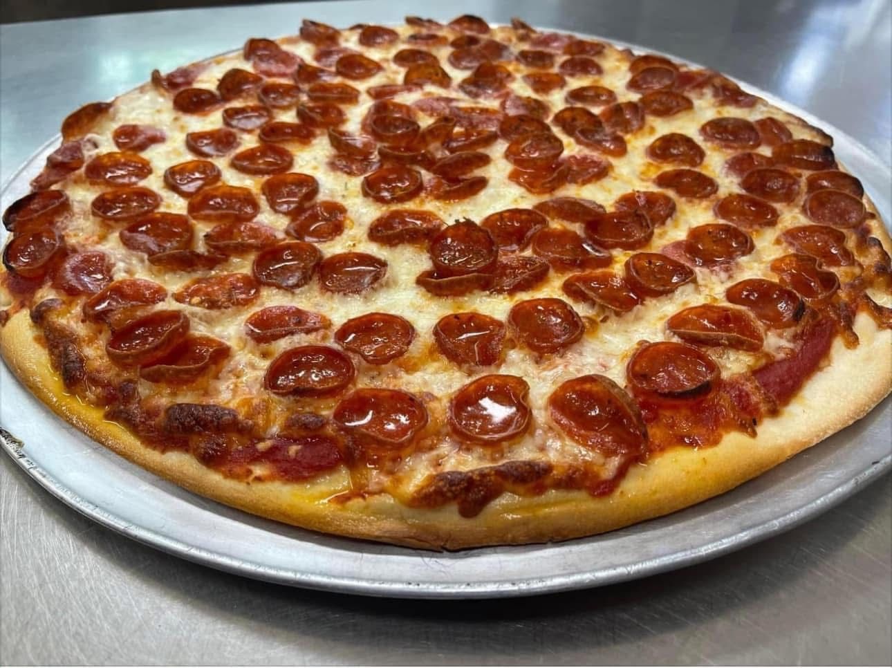 A pepperoni pizza is sitting on a pan on a table.