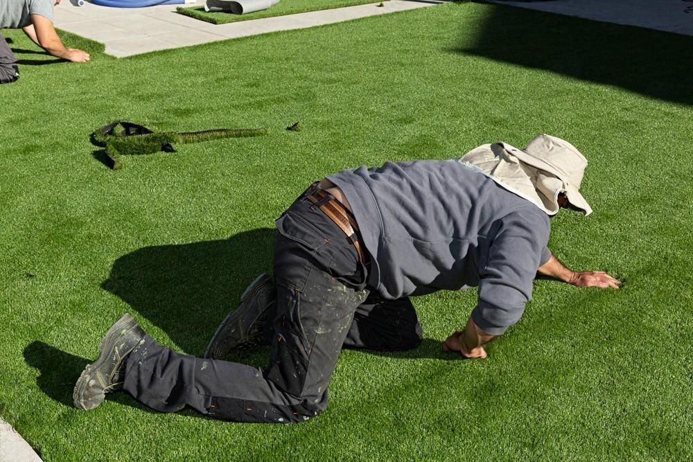 a man wearing a hat is kneeling on the grass .