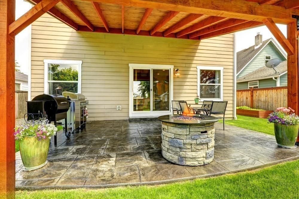 there is a fire pit on the patio under a pergola .