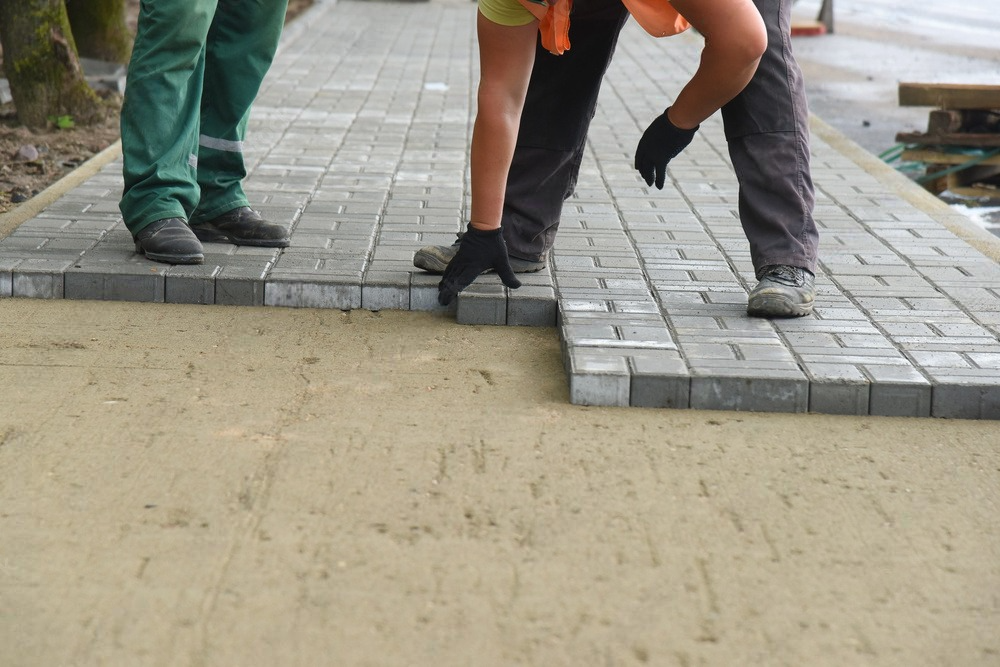 a group of people are working on a sidewalk .